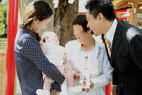 お宮参り写真 自宅 新田神社 鳥居の前で赤ちゃんを見る